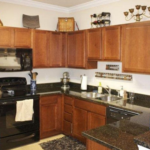 Apartment kitchen with dark wood cabinets and black countertops and black appliances