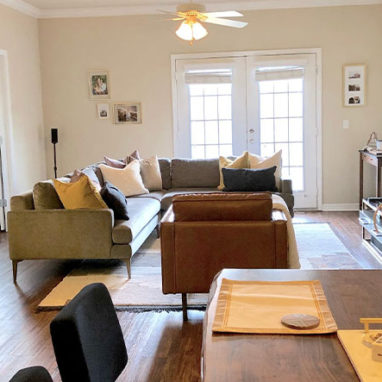 View of living room from dining room with couch, chair and TV on an entertainment center.