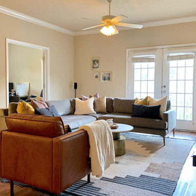 Alternate view of living room furnished with couch, chairs and TV.